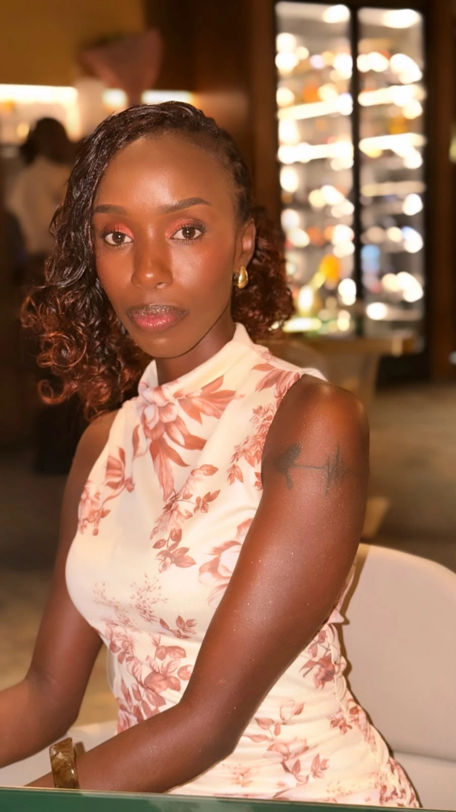 Beauty portrait of ZuriNiah, Doreen Kathambi Gikundi, in a sleeveless ivory blouse with a rust floral print