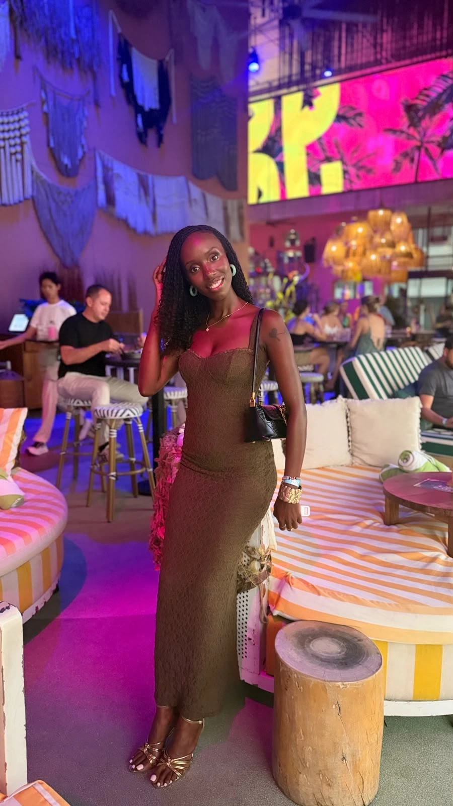 ZuriNiah, Doreen Kathambi Gikundi, smiling in a floor-length olive lace dress and gold heels