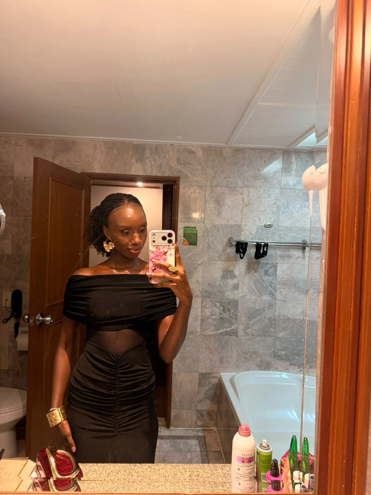 Mirror portrait of ZuriNiah in a black off-shoulder dress with a sheer midriff, looking toward her phone