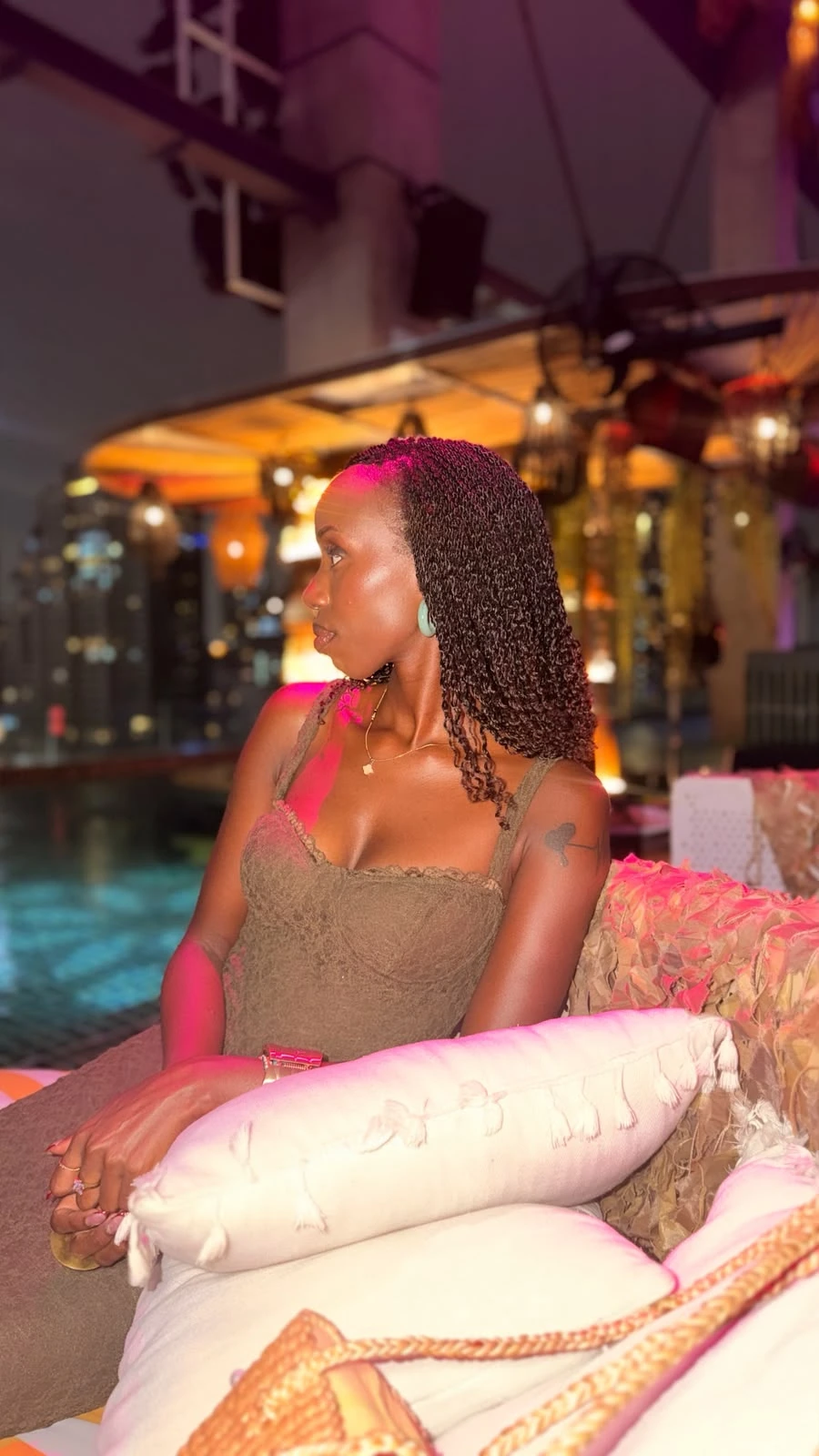 Beauty portrait of ZuriNiah in profile, seated by a pool at night in an olive lace dress