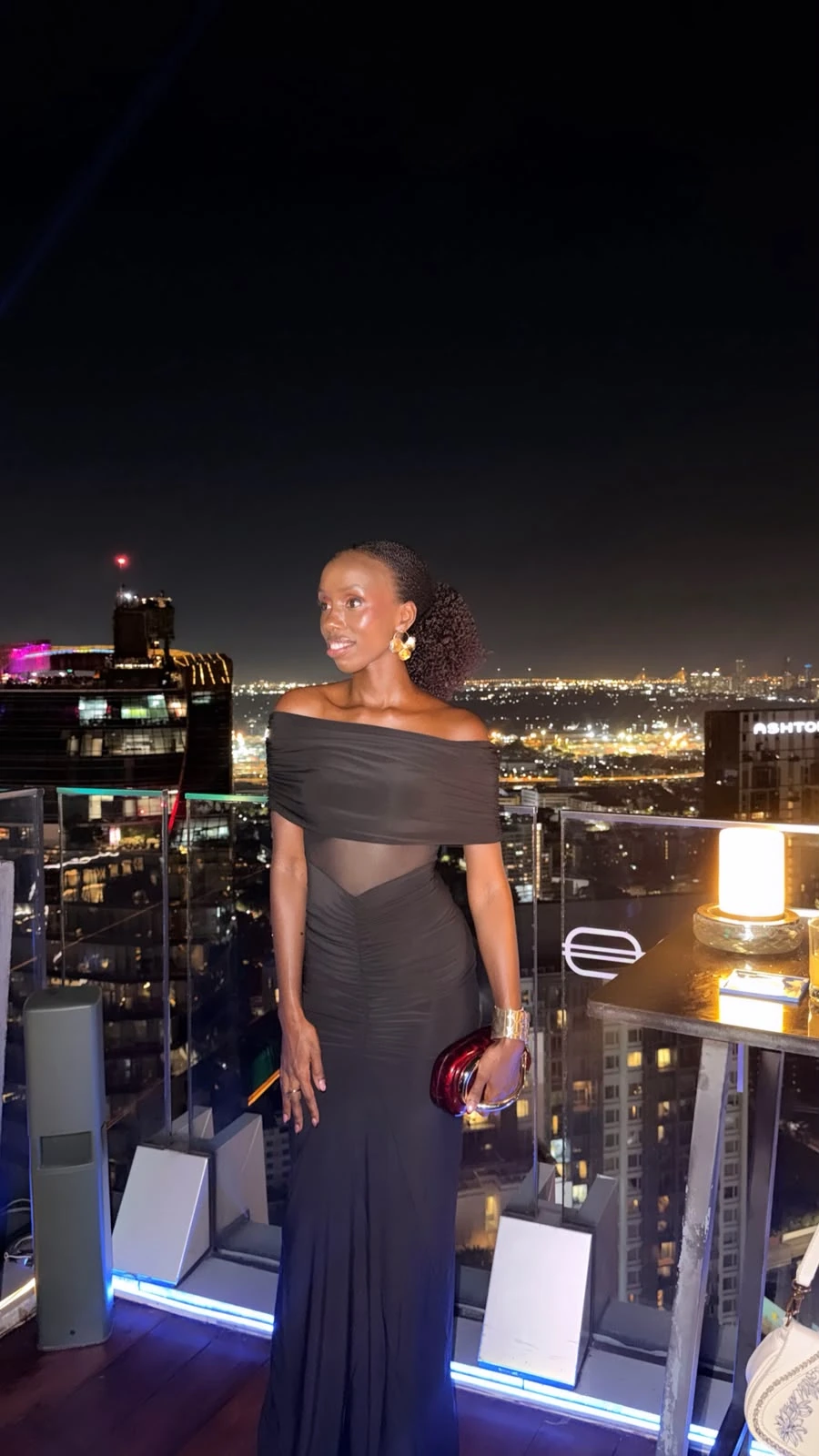 ZuriNiah, Kenyan model Doreen Kathambi Gikundi, standing on a Hong Kong rooftop at night in a black off-shoulder gown